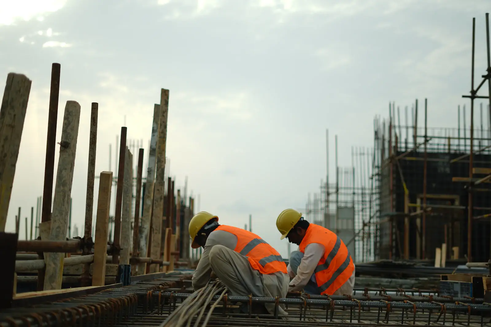 Construction workers in hard hats fixing steel reinforcement for concrete columns