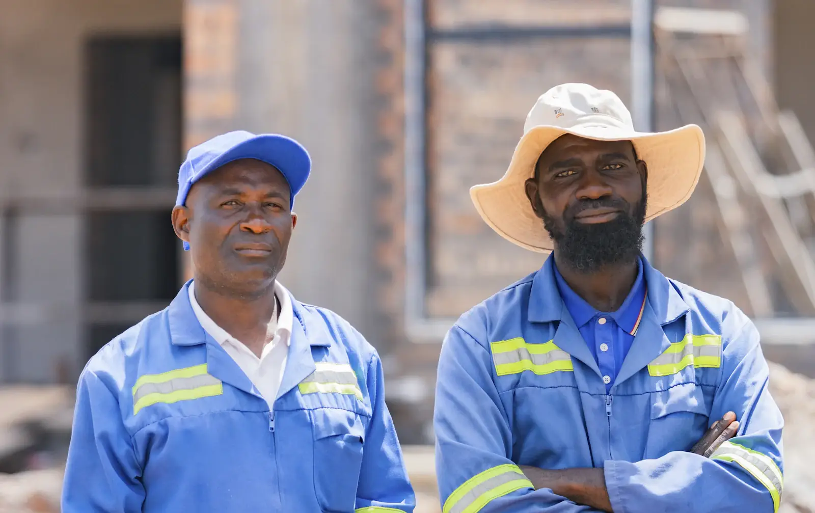 Two site supervisors in blue work uniforms standing in front of a building
